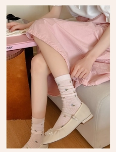Detail of pink floral embroidered socks paired with cream Mary Jane shoes in soft light