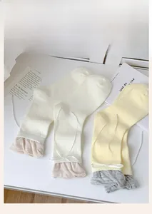 Detail of sweet ballet-style socks with silk ribbons and ruffles on white wood