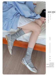 Detail of grey knitted mid-calf socks with light blue bow and silver Mary Jane shoes