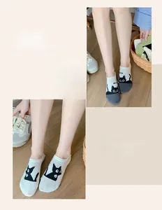 Detail of grey low cut socks with cat pattern and contrast toe on wooden floor