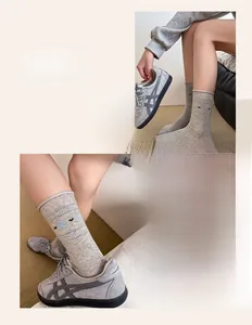 Close-up of light grey crew socks with black hearts and blue patterns on rolled cuffs