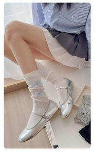 Detail of white mesh mid-calf socks with blue checkered bows and silver Mary Jane shoes