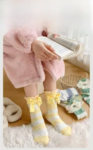 Gros plan de chaussettes en polaire corail à rayures avec nœuds dans un décor chaleureux