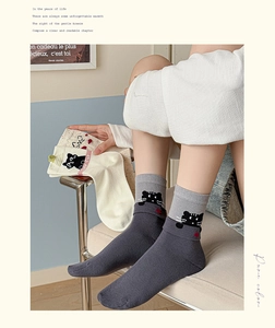 Detail of embroidered cartoon cat on ribbed cuff of mid-calf cotton socks for women