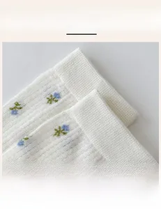 Detail of high-elastic ribbed cuff and delicate blue floral embroidery on white socks