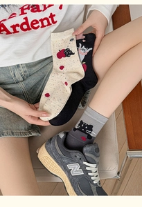Detail of cotton socks showing cute cartoon cat and red apple patterns on ribbed fabric