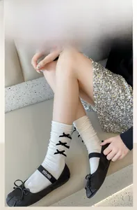 Detail of cream calf socks with black bows and ribbed texture worn with ballet flats