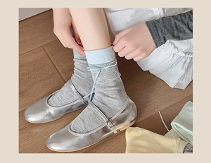 Detail of grey balletcore mid-calf socks with blue ribbon bows and silver Mary Jane shoes