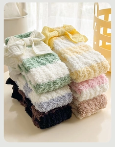 Détail de chaussettes rayées en polaire corail avec de grands nœuds décoratifs doux