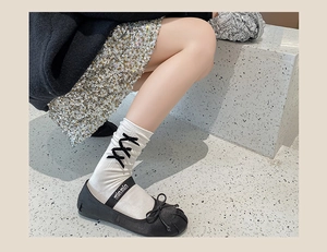 Detail of cream calf socks with black ribbon bows paired with ballet flats