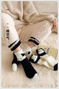 Gros plan de chaussettes panda en peluche épaisse avec oreilles 3D sur tapis blanc