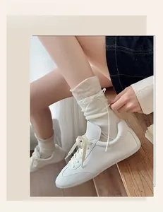Detail view of beige mid-calf socks with delicate ribbon bows and white leather sneakers