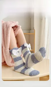 Détail de chaussettes chaudes en polaire corail à rayures bleues et nœuds blancs