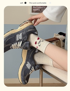 Detail of oat-colored crew socks with colorful dots and a cute cartoon cat embroidery