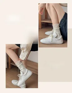 Close-up of white leather sneakers with cream laces and ribbed knit crew socks
