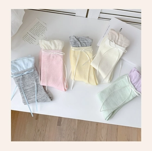Detail view of five pairs of pastel knit socks featuring elegant white ribbon bow accents