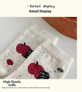 Detail view of ribbed elastic cuff on cotton socks with cute cat and apple patterns