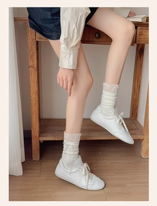 Detail view of white leather casual shoes paired with sweet ribbon ballet style socks