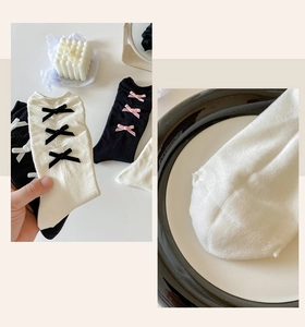 Detailed close-up of bow-decorated ballet style socks with reinforced toe stitching