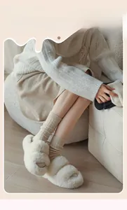Dettaglio calze in maglia a coste beige con pantofole di peluche in ambiente domestico