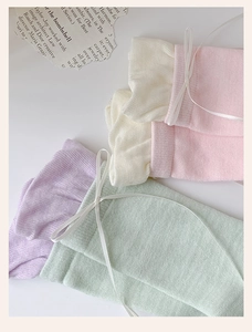 Detail of macaron color knitted socks with ribbon bows and ruffled cuffs in four pastel shades