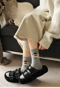 Détail de chaussettes en laine grise avec motif chiot et pantoufles en peluche noire