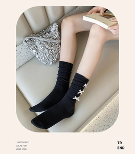 Detail view of black knee high socks with three white bows and a soft knitted texture