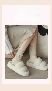 Dettaglio di pantofole accoglienti in ecopelliccia beige con calze a coste coordinate