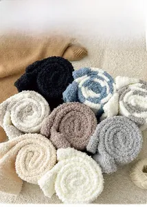 Close-up of cozy thick coral fleece leg warmers in various colors on a plush white rug