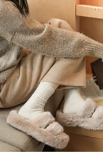 Close-up of thick beige wool socks featuring a cute brown bear embroidery detail