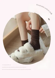 Dettagli di calze a coste marrone scuro abbinate a calde pantofole di peluche beige