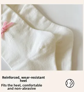 Detailed shot of white ribbed knit socks featuring reinforced heel and pink velvet bow