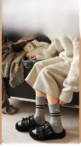 Detail of wool socks with striped trim and cute puppy embroidery worn with plush slippers