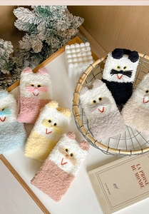 Close-up of cozy coral fleece socks featuring cute 3D cat embroidery and colorful stripes