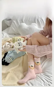Close-up of thick coral fleece socks with embroidered cartoon eyes in diverse colors