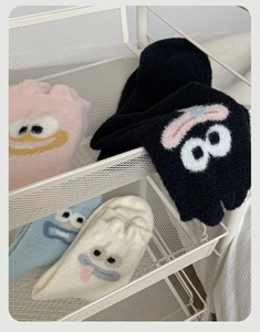 Detail of four colorful fuzzy socks with cartoon monster faces in a white basket