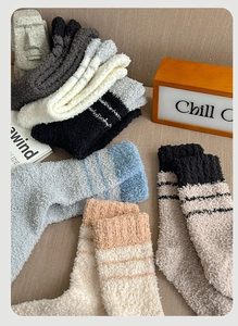 Close-up of thick coral fleece winter socks with striped design in various warm colors