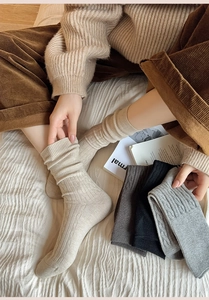 Detail of warm knit mid-calf socks with ribbed texture and cable pattern in neutral colors