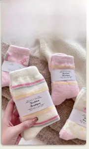 Nahaufnahme dicker rosa Korallenfleece-Socken mit süßen Cartoons und Streifenmuster