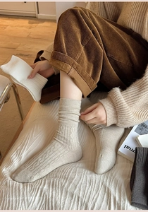 Close-up of thick cable knit winter socks in beige, white and grey with ribbed texture