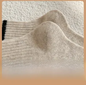 Detail of oatmeal knitted wool sock heel with black stripes on a cozy white fleece surface