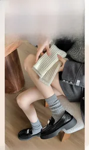 Dettaglio della trama a maglia di calze spesse a costine beige e grigie con scarpe nere