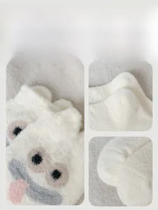 Detail view of plush white monster socks with embroidery eyes and pink tongue
