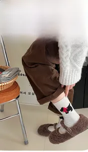 Close-up of fluffy white socks with dog embroidery and red bow in warm lifestyle setting