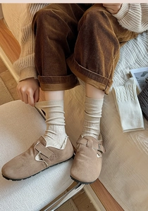 Detail of warm brown suede mules with soft fleece lining and beige ribbed knit socks