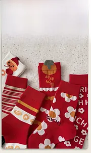 Dettaglio di calze festive rosse in cotone con motivi tessuti di cachi e lingotti d'oro