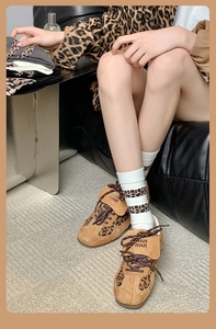 Nahaufnahme der Leopardenmuster-Socken mit braunen Sneakers und Miu Miu Logo im Vintage-Stil