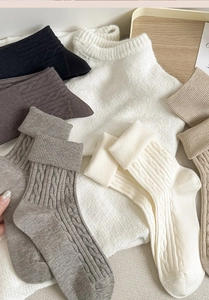 Detail of cable knit wool socks in earthy tones with ribbed cuffs for winter warmth