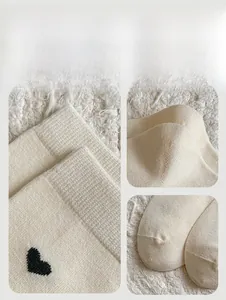 Dettaglio calzini in maglia crema con ricamo a cuore nero e polsini a coste rinforzati