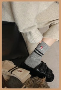 Detail of wool socks featuring black stripes and a cute dog embroidery on grey knit fabric
